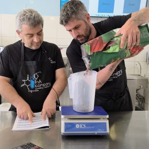 Δύο άτομα σε κουζίνα, ζυγίζουν υλικά.